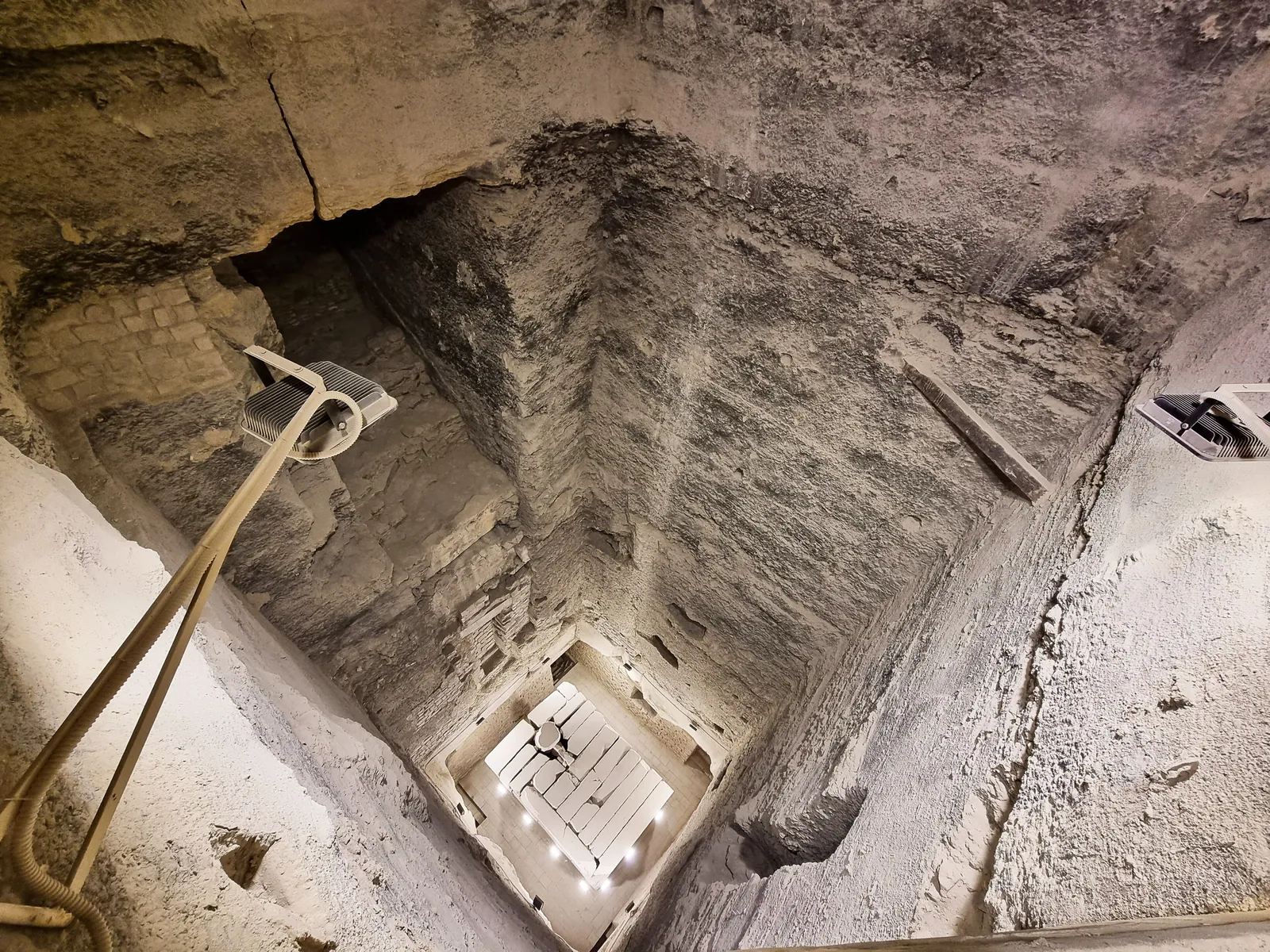 Slutet på vägen genom den södra ingången: blicken ned i det 7 × 7 m breda och 28 m djupa centralschaktet mot den belysta gravkammaren av granit på botten (2022).