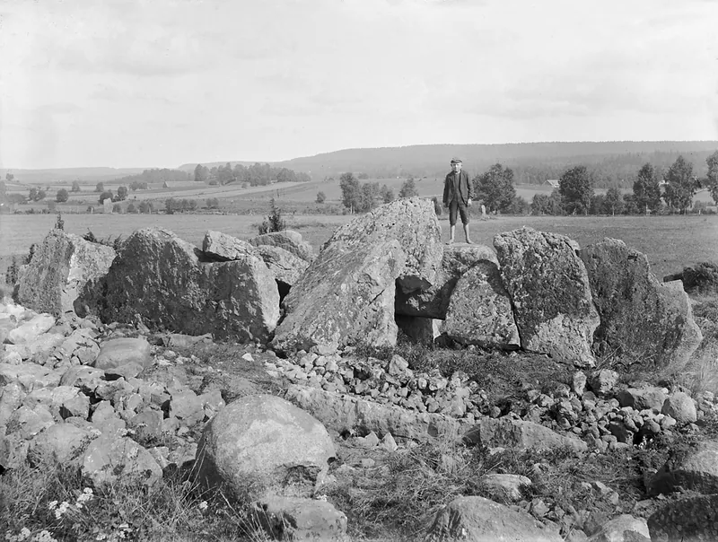 En pojke står på en gånggrift på Ekornavallen, glasplåtsnegativ från omkring 1900 (Riksantikvarieämbetet). Falbygden har över 250 dösar och gånggrifter – ett av norra Europas tätaste megalitlandskap.
