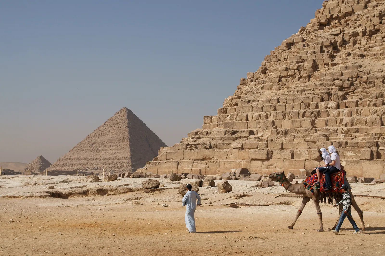 Kamelritt vid foten av den stora pyramiden, med Chefren och Mykerinos bakom. Djurritterna håller på att fasas ut på platån (uppgifter sommaren 2026) – och det är här som pristricket börjar.