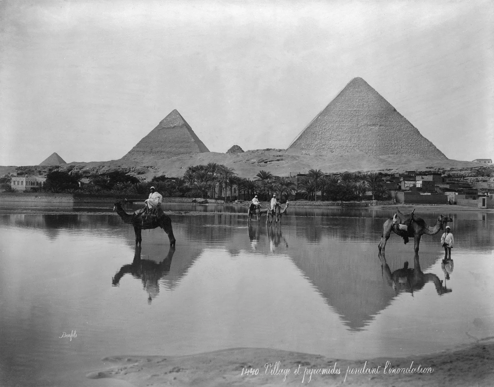 ”By och pyramider under översvämningstiden”, fotograferat på 1890-talet (Frank och Frances Carpenters samling, Library of Congress): män och kameler vadar genom de dränkta fälten nedanför Giza. Fram till Assuans högdamm (färdig 1970) nådde översvämningen platåns fot varje höst – årstiden då sten kunde flottas nära byggplatserna.