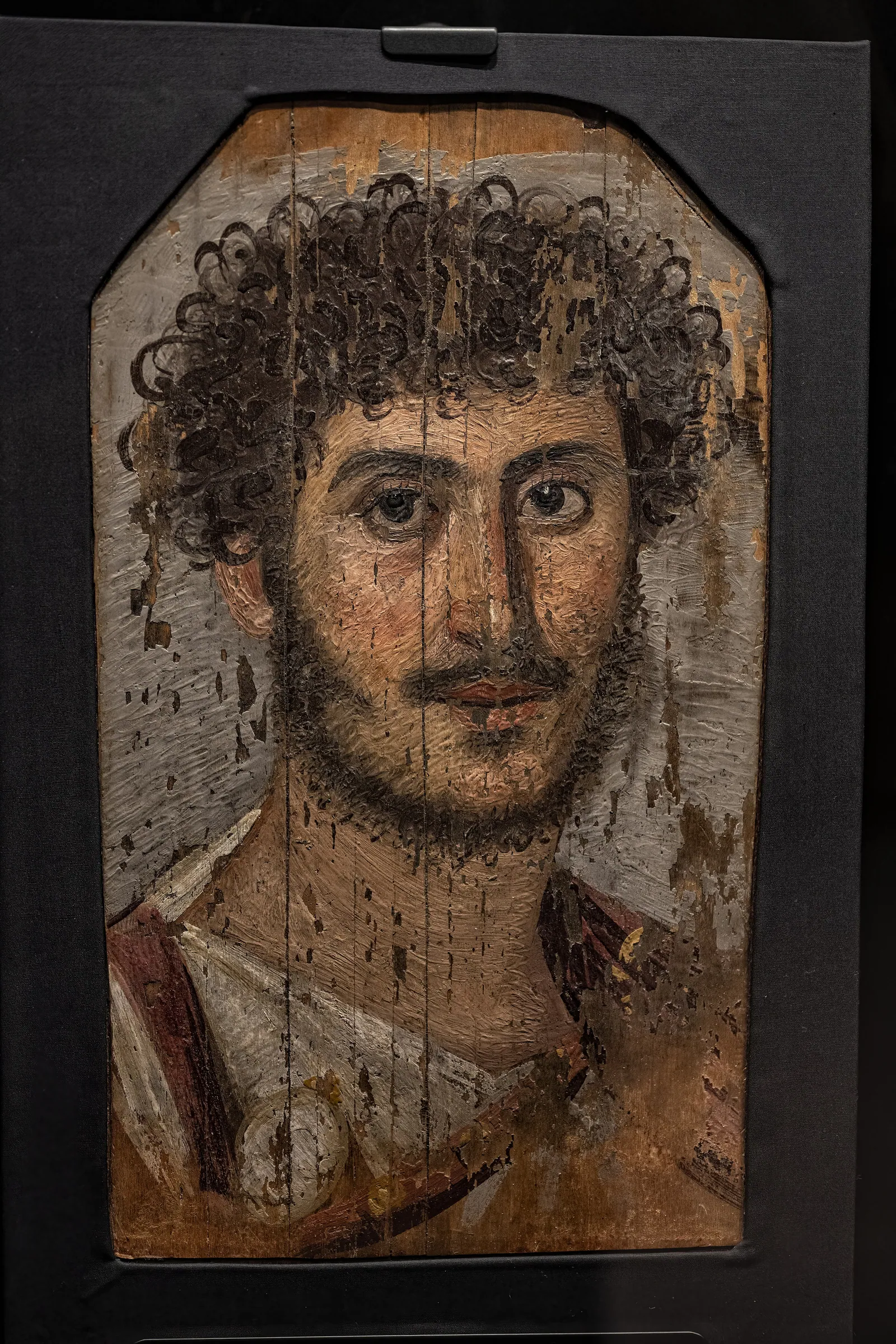 En man med svärdsbälte (balteus), målad i Hawara ca 185–195 e.Kr. (Manchester Museum). Petrie såg att många av mumierna hade stått framme i åratal innan de begravdes – ett fotfodral hade till och med barnklotter på sig.